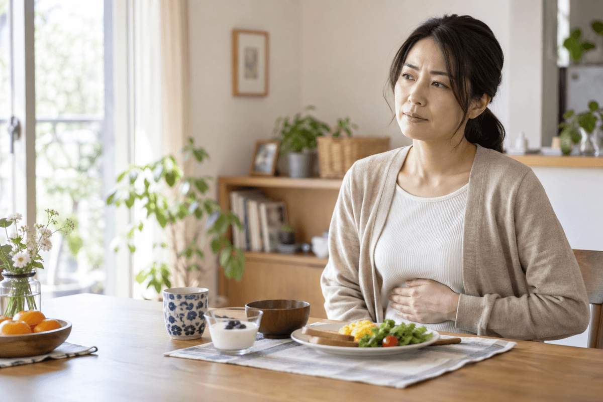 朝食を途中で止め、みぞおち付近の違和感を落ち着いて確かめる女性